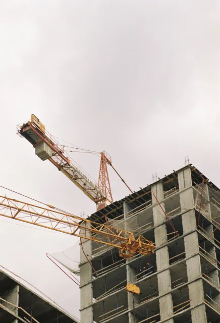 Stock reference: tower cranes above a concrete building structure.