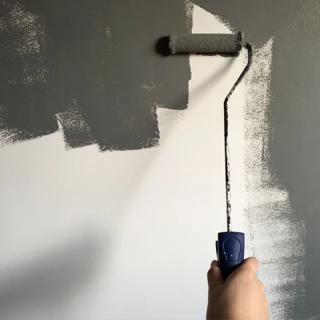 Stock reference: a hand applying wall paint with a roller.