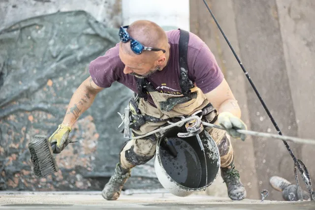 Stock reference: a worker repairing and finishing a building facade.